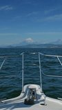 On the bow of the boat. Along the coast of the Kamchatka Peninsula with volcano, Russia. Vertical video