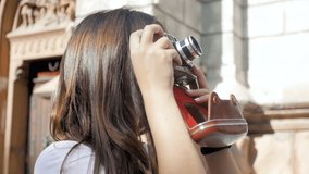 Closeup steadicam video of beautiful brunette girl making photographs on vintage film camera