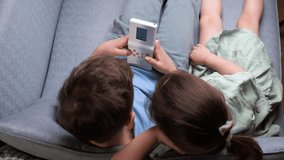 top view of children boy girl playing old vintage handheld console video game