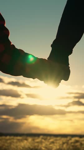 Father pulls her hand to child, son takes his Father by hand in rays of sunset, close-up. Happy family, dad, son hold hands close-up, teamwork. Parent, child, Concept of trust, safety family. Kid sun