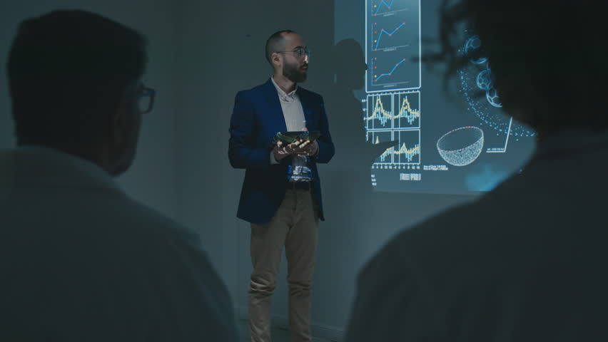 Full shot of Middle Eastern male research scientist talking about innovative discovery of new drug to doctors in white coats at medical conference, demonstrating slide on screen, audience clapping Royalty-Free Stock Footage #3470815979