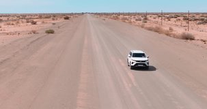 Drone video of a four-wheel drive vehicle driving on a gravel road in a desert area in southern Namibia during the day in summer
