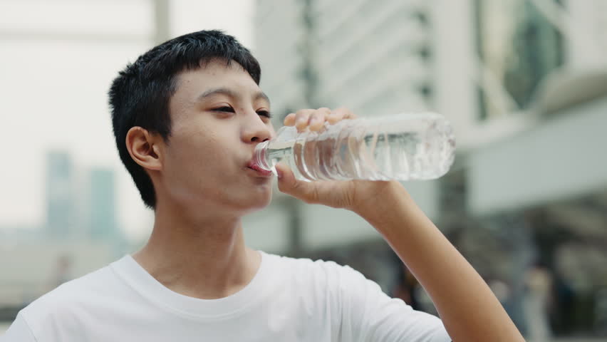 Close View of the Asian Teenage Guy Outside Drinking Water in Training. Athletic Young Football Player with Drink for Refreshing. Football and People Concept