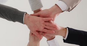 Group of a business people joining hands in stack. Close up of company employees putting their arms in a pile together. The concept of unity and teamwork. Low angle view. 4k video. Slow motion video.