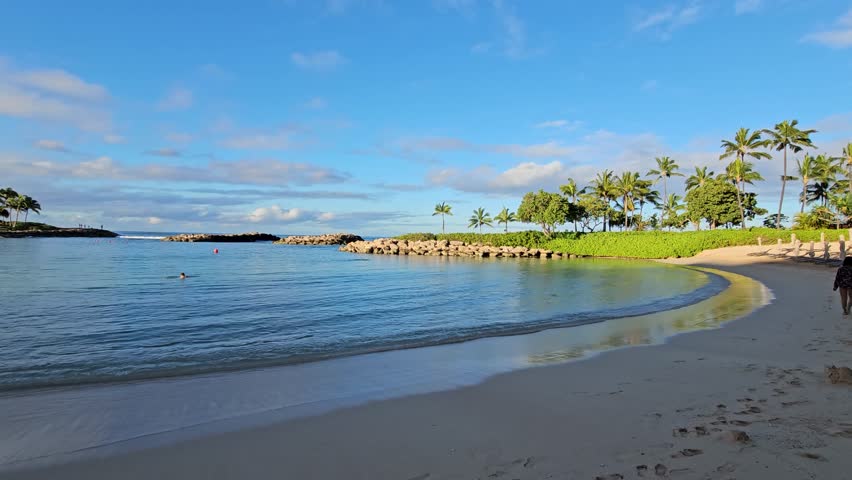 panning footage of the Ko Olina Lagoon and the pacific ocean with lush green palm trees, plants and grass at sunrise at Ko Olina in Kapolei Hawaii USA