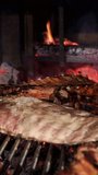 slow motion vertical video of pork ribs cooking slowly on a restaurant charcoal grill