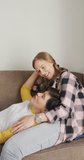 Vertical video of happy caucasian lesbian couple embracing at home. spending time together at home.