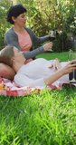 Vertical video of caucasian lesbian couple drinking wine in garden. spending time together at home.