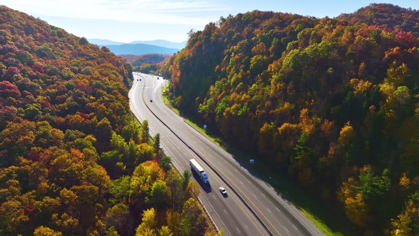 I-40 freeway in North Carolina leading to Asheville through Appalachian mountains in golden fall with fast moving trucks and cars. Interstate transportation concept