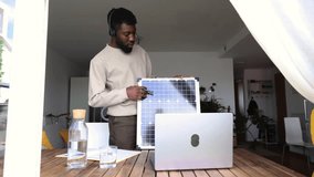 A professional African American consultant conducts a remote presentation, pointing out features on a solar panel, from his home office. Remote Solar Technology Consultant Giving an Online Presentatio