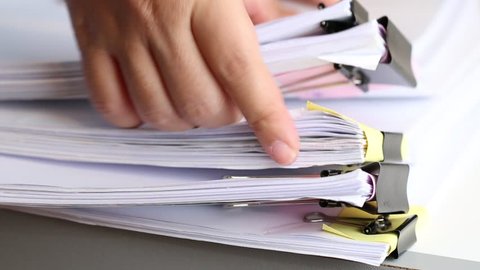 Businessman hands searching unfinished documents stacks of paper files on office desk for report papers, piles of papers sheet achieves with clips on desks, Document is written, drawn,presented.