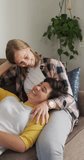 Vertical video of happy caucasian lesbian couple embracing at home. spending time together at home.