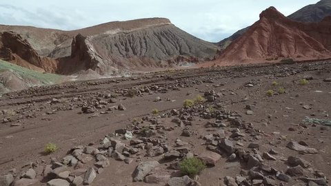 Flyover of rocky and craggy terrain, showing salt deposits as the camera approaches a tall ridge. Filmed in the Atacama Desert in Chile 