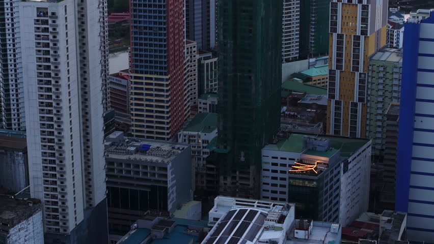 Modern high rise residential building in metropolis. Tilt up reveal harbor and ships along sea coast at sunset. Manila, Philippines