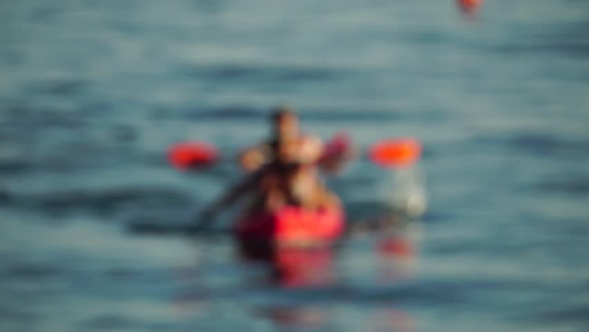 Defocused sea ocean beach of hotel or resort with Lounge bed on hot summer day. Abstract bokeh background of blurred resting and swimming people on beach at blue sea. Holiday, vacation and recreation.