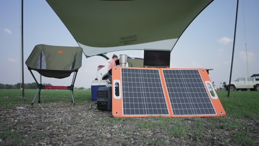 An inviting outdoor mobile workspace with a solar panel charging a laptop, under a protective canopy, showcasing sustainable energy in a remote setting