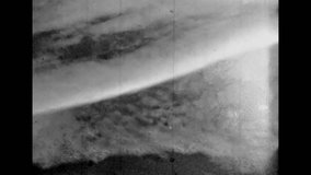 Close-up, monochrome film of sea foam on sand. Seascape sky horizon over sea. Abstract tide of sea waves on sandy coast. Ocean beach landscape. Overscan footage. Vintage black white retro archive 1980