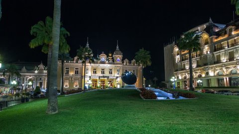 Square with Grand Casino in Monte Carlo night hyperlapse timelapse, Monaco. Historical buildings around. Palms on the side. Parking and traffic on the road