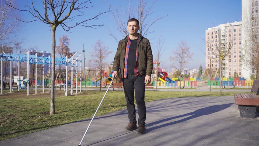 Blind man with cane walking alone on the road.
