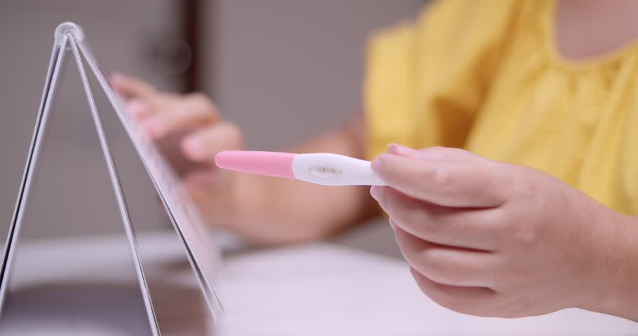 Expectant mother going through a calendar to count the weeks to her expected due date while holding a pink pregnancy test kit on her left hand. Royalty-Free Stock Footage #3471692253