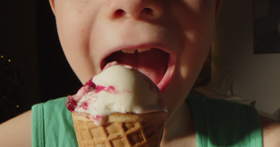 Close-up of child's mouth, a little boy eating a waffle cup with vanilla ice cream and strawberry ice cream. Close up portrait of cute boy eating waffles cone ice cream. Child licking ice cream. 4K