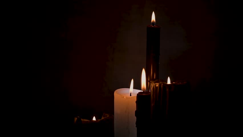 Female hand lighting black candles for occult ritual, Halloween and witchcraft, close-up.