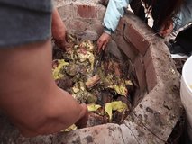 Video of unknown people taking the pachamanca out of an oven. Concept of food preparation.