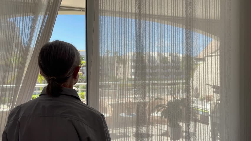 Bonding senior family couple at home looking out of the window expressing melancholy, elderly retired man and woman support each other