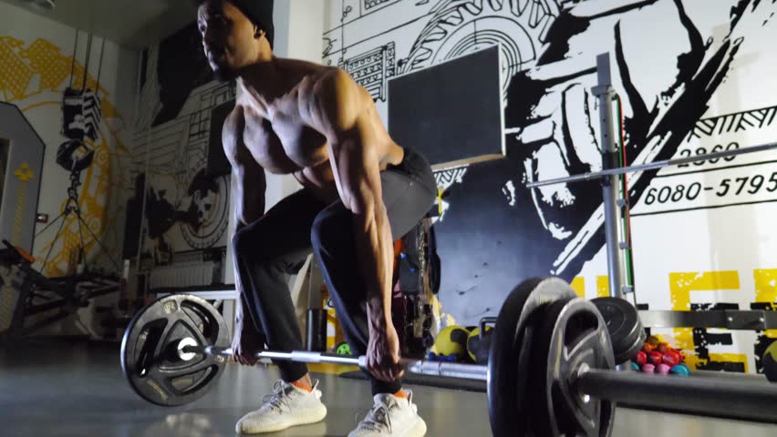 Athletic black man doing deadlift with heavy barbell at modern gym. Muscular african guy doing weightlifting exercises at sport club. Young afro american sportsman working out at fitness centre