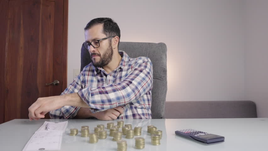 Man doing accounting and counting money coins makes a happy satisfaction face. Savings, entrepreneurship dreams earnings goals