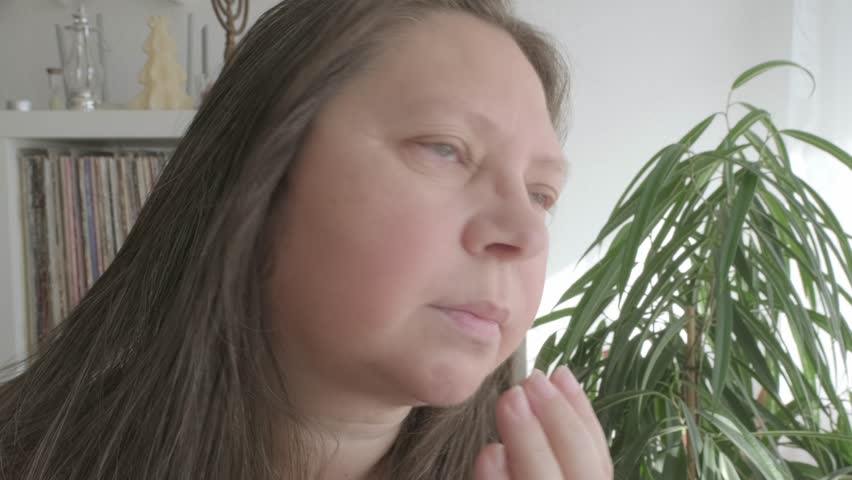 self-aware woman 50 years of age, takes moment to assess her facial features, particularly jowls, reflecting on natural process of aging and considering options for maintaining youthful appearance Royalty-Free Stock Footage #3471838423