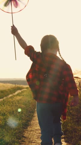 the pinwheel begins to play, child kid runs through park windmill hands, smile face, hand spinning sun, children dream, happy little girl child kid playing with a windmill at sunset, children running