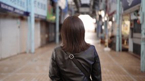 Slow-motion video of an Okinawan woman in her 20s in winter clothes walking in a shopping street near Kokusai Street in Naha City, Okinawa Prefecture