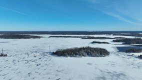 Aerial video over a frozen lake and island with trees