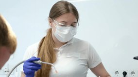 latest technology cleaning and whitening teeth nurse and doctor treating the teeth of a young female patient teenager masks gloves cleanliness sanitation. latest device in dental office in a clinic