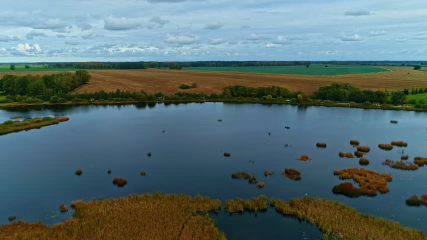 Countryside lake with small islands, aerial drone side fly view