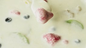 Spoon mixing yogurt with fruits and berries full hd slow motion close up video. Milk shake. Dairy food and milkshake beverage sweet dessert cooking