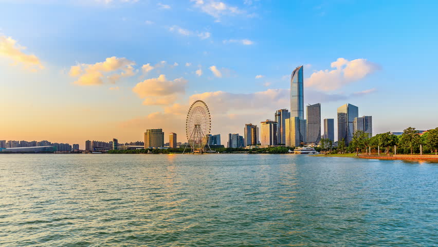 Suzhou skyline and modern city buildings scenery at sunset by the lake. Beautiful Jinji Lake landscape in Suzhou. 4k time lapse video.