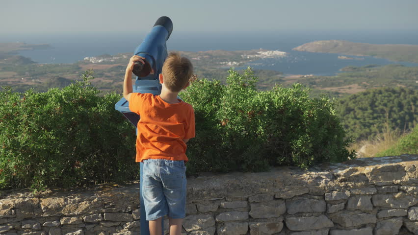 Little boy looking through the telescope the mountain top panorama