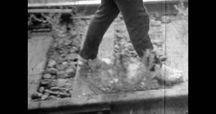 Man legs walk along railway tracks, close up. Vintage black white film. Retro archive 1980s. Walking along train tracks in countryside. Adventure travel by railroad transportation. Old wood rail road