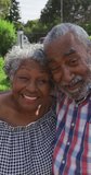 Vertical shot of a senior African American couple having a video call, smiling and waving at the camera. Seniors and technology concept.