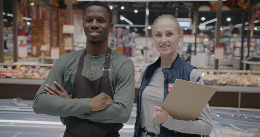 Slow motion portrait of man and woman supermarket workers standing in shop smiling looking at camera. People and retail business concept. Royalty-Free Stock Footage #3472363549