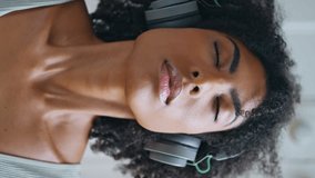 Serene model practicing yoga breathing. Closeup african woman face meditating inhaling slowly at white room vertically video. Closed eyes girl making deep breath-exhalation listening headphones music  - Powered by Shutterstock - Get 15% off with code: PIKWIZARD15
