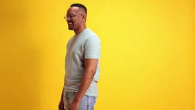 Happy and excited African-American man smiling and spreading hands against yellow studio background. Positive surprise. Concept of human emotions, casual fashion, lifestyle, sales, news