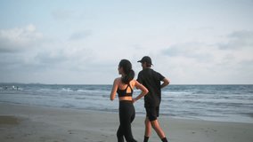 Back view of asian sports couple running at seashore with dramatic sky and bright sunset. Man and woman jogger during outdoor activity on beach. 4k resolution and slow motion shot. - Powered by Shutterstock - Get 15% off with code: PIKWIZARD15