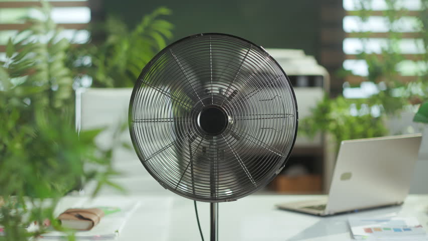 Summer time. metal fan in modern green office.
