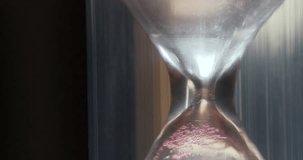 Red sand in hourglass. Time flows backwards, in opposite direction. Time is like sand in endless desert, but remember, your handful is in hourglass. 4K macro shot reverse time and turned over video