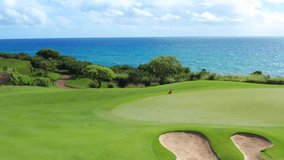 Dream green golf course at ocean in Hawaii. Red flag waving on putting green hole. Aerial above green golf course clear transparent blue ocean water. round  shaped sand trap bunker - Powered by Shutterstock - Get 15% off with code: PIKWIZARD15