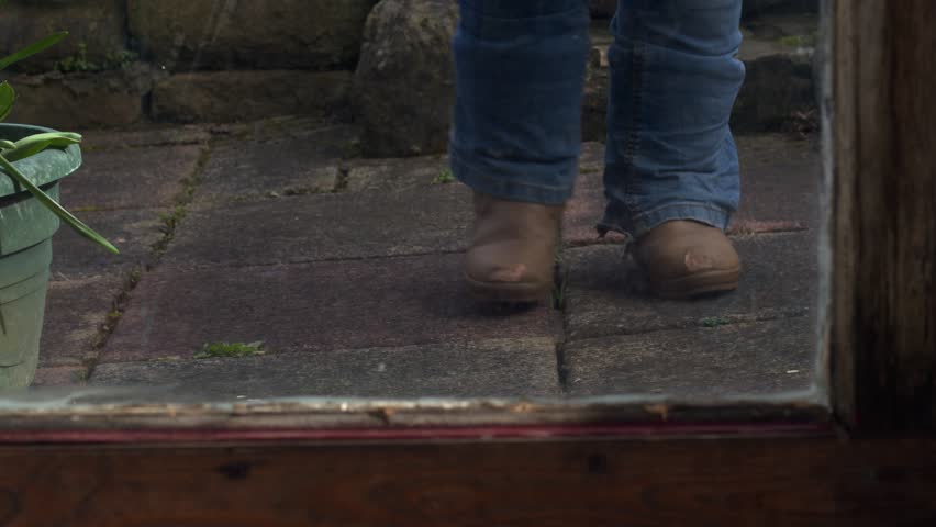 Woman brings in laundry basket view through kitchen door medium shot 4k selective focus