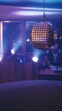 vertical video In dark club, disco ball hangs mirror-ball ceiling. disco ball glitterball in bar. intimate atmosphere in the restaurant dimmed light smoky room. light effects in nightclub dancefloor